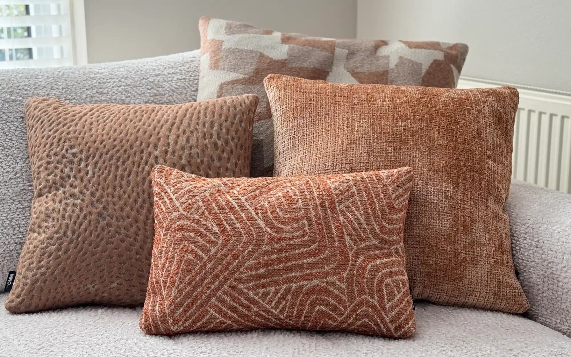 Sfeervolle combinatie van grote en compacte sierkussens in terracotta en perzikkleur