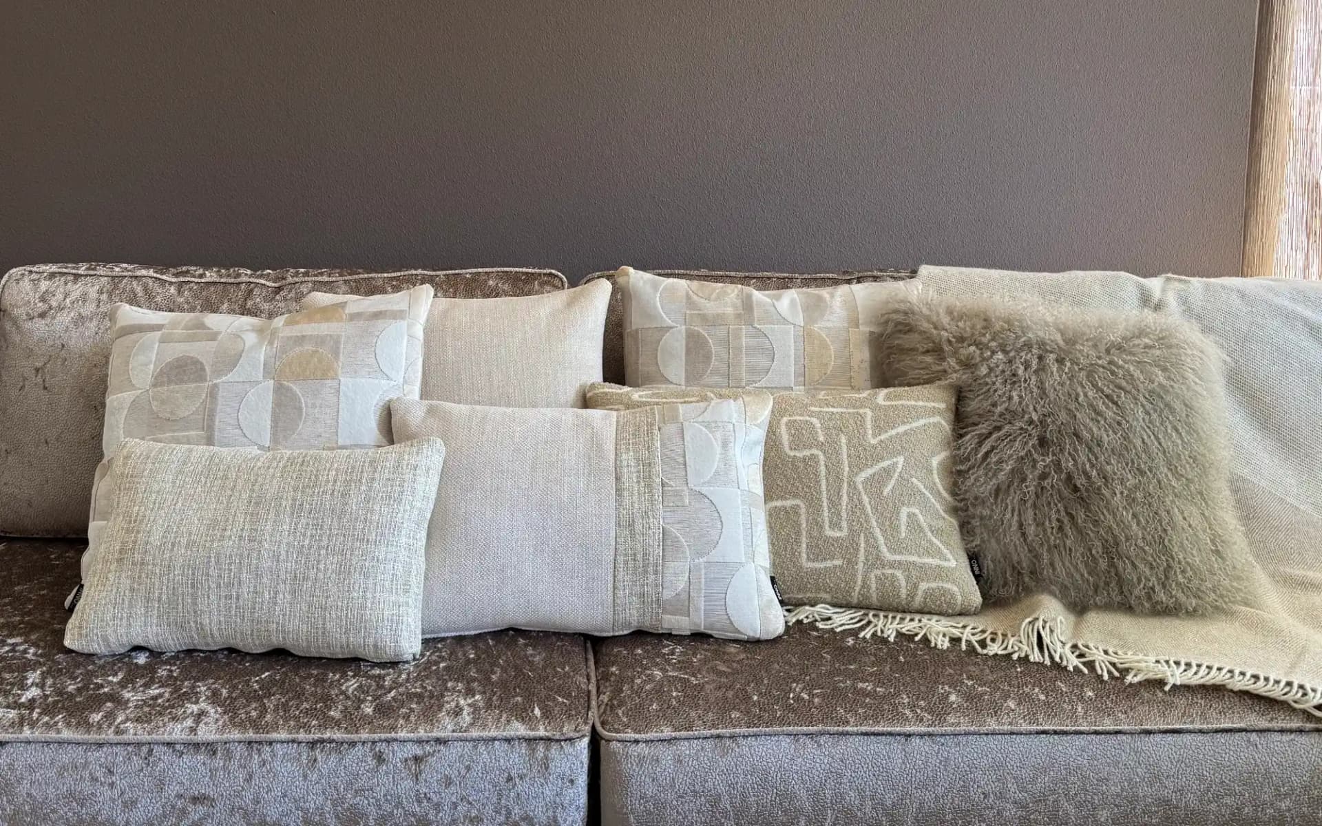 Sfeerfoto beige en zandkleurige sierkussens gecombineerd met plaid en schapenvacht sierkussen