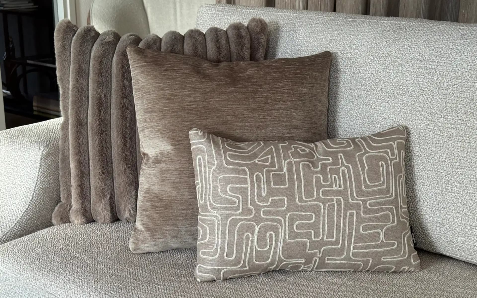 Sierkussen set Loft Brown met drie bruine sierkussens op een bank