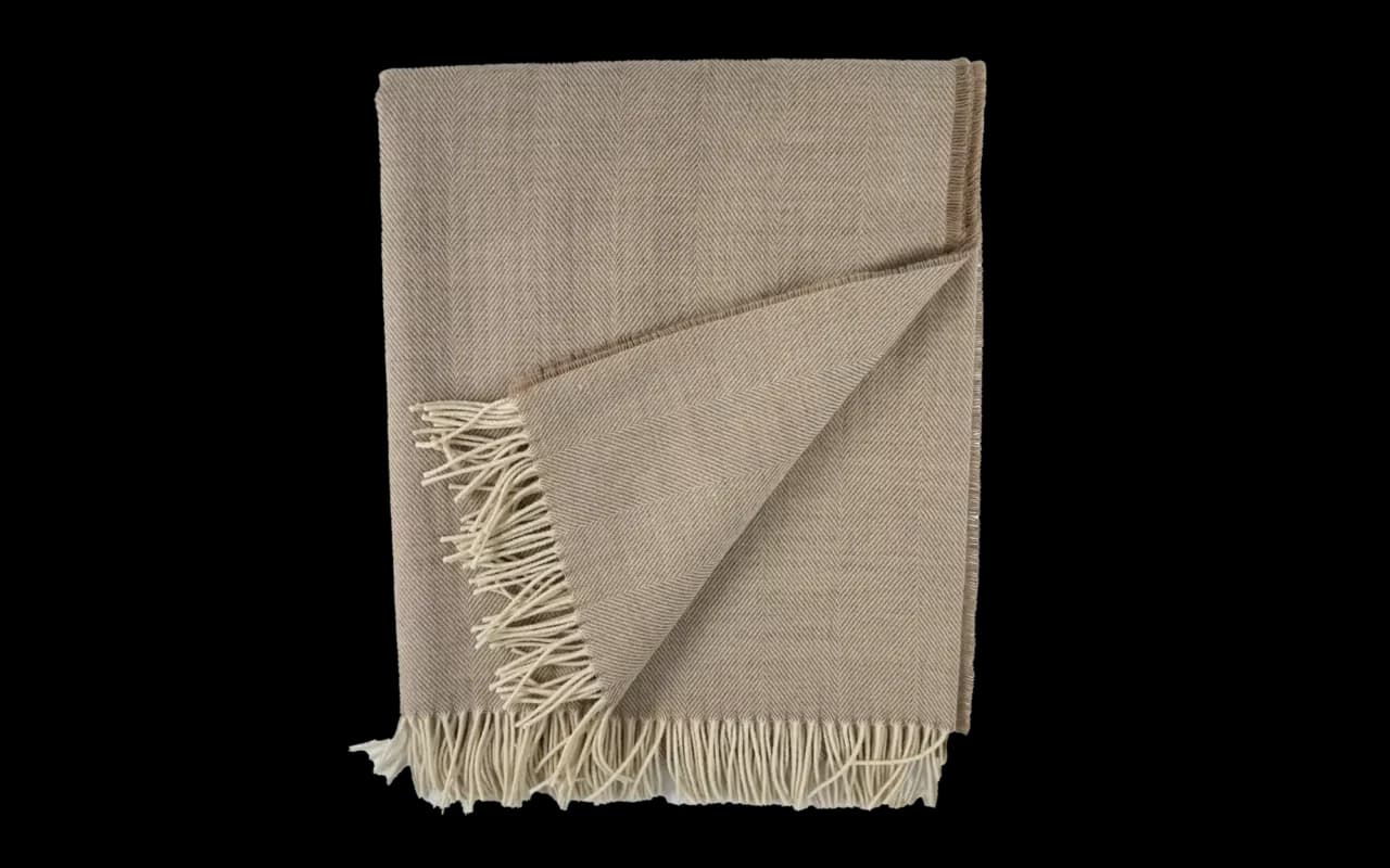 Opengeklapte merino plaid in warme bruine tint, detail zichtbare textuur.